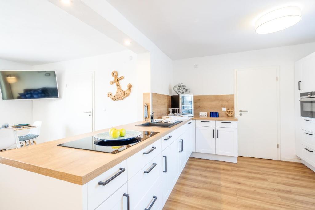 una cucina con mobili bianchi e un piano di lavoro in legno di Strand Familien Doppelhaushälfte ,,MARSI'' #Familien-Urlaub a Rappin