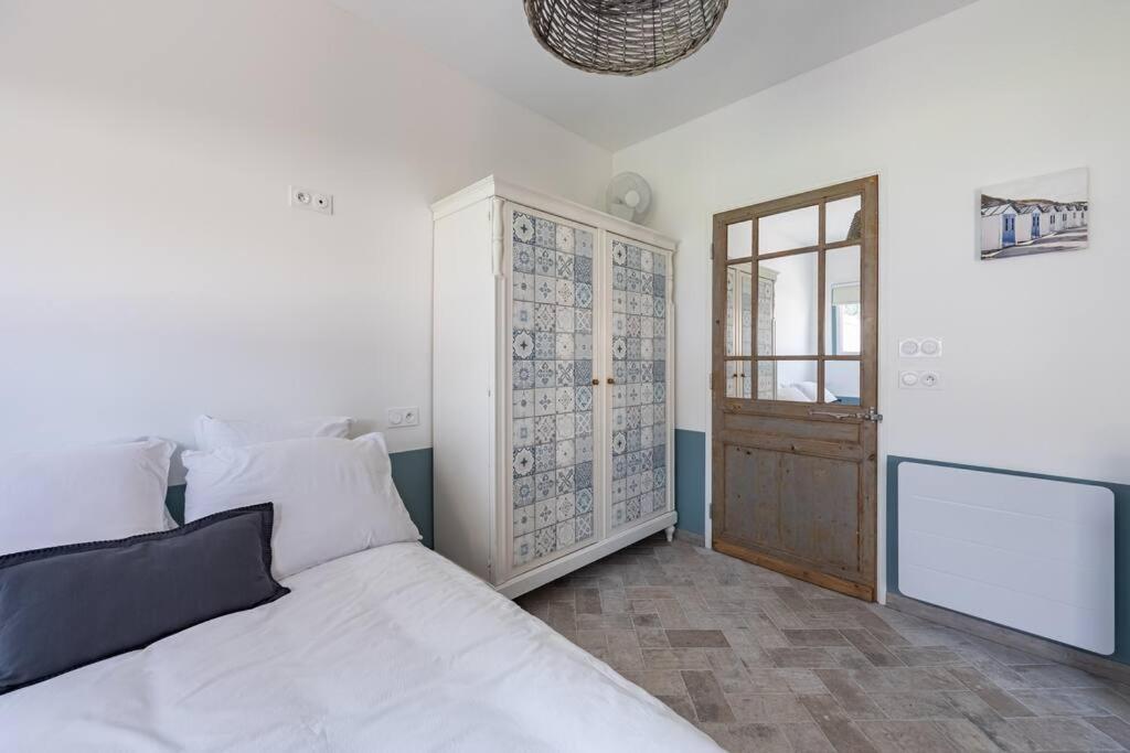 a bedroom with a white bed and a wooden cabinet at Plain pied avec terrasse à 5 minutes de Berck in Verton