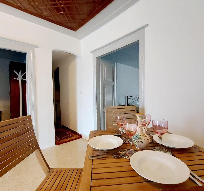 a wooden table with two plates and wine glasses at Danaë Port House in Hydra