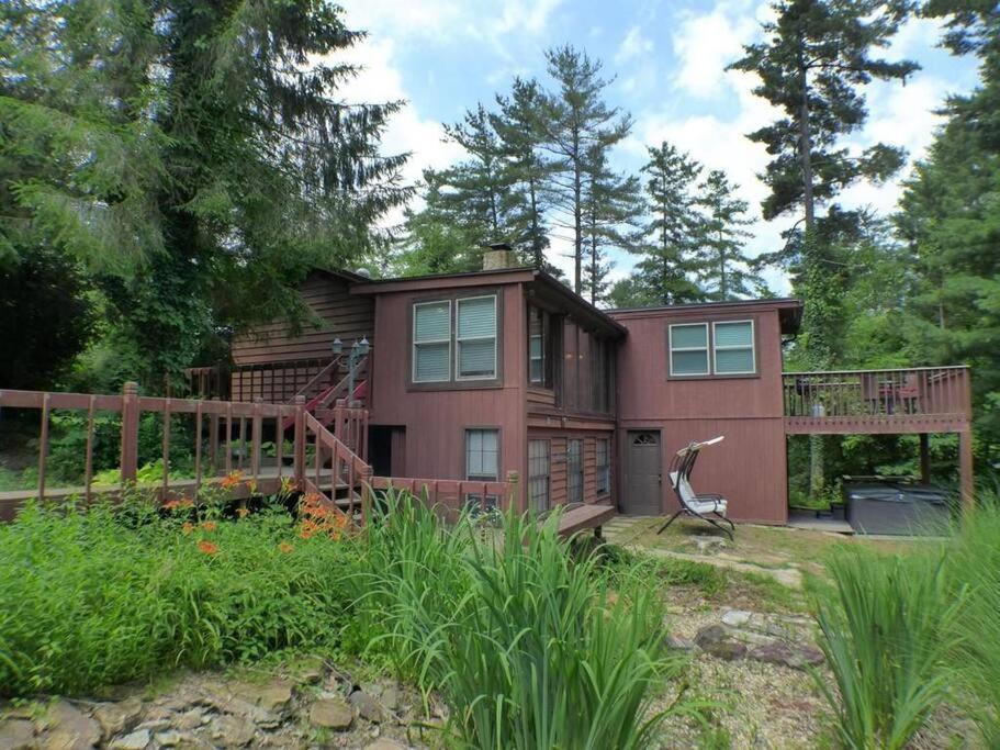 a large house with a deck and a fence at Hocking Hills Cottage with beautiful pond in Logan
