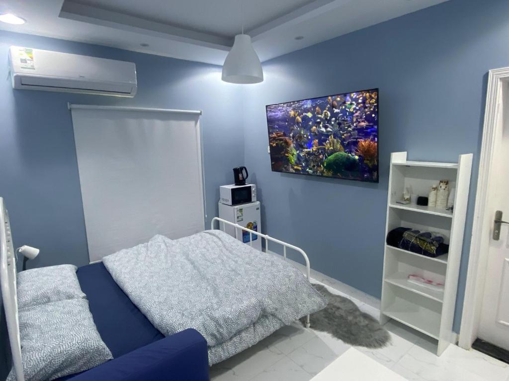 a blue room with a bed and a painting on the wall at Eco Room in Jeddah