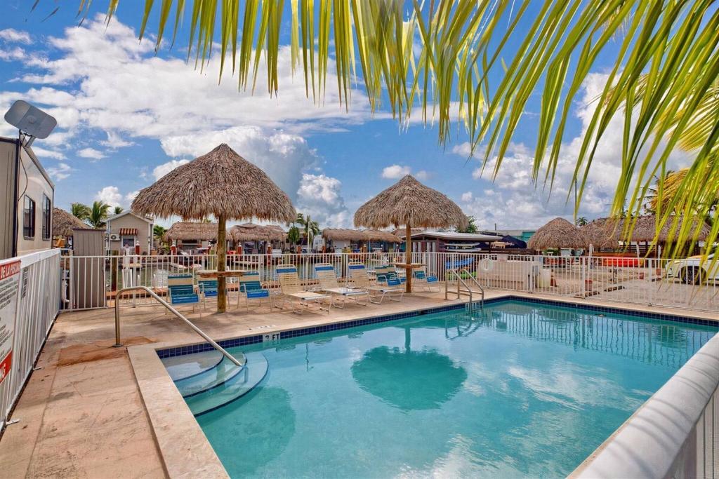 uma piscina com guarda-sóis de palha e espreguiçadeiras em Tiny Home on Waterfront, Bay Views, Deck, Pool em Jewfish