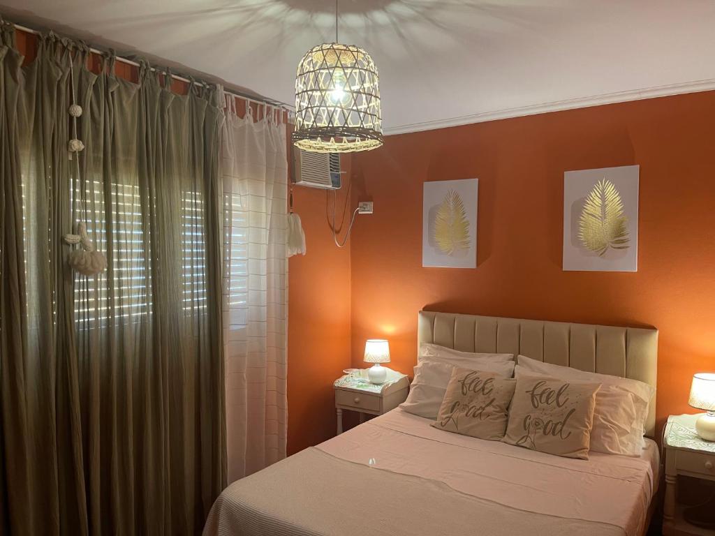 a bedroom with orange walls and a bed with a chandelier at Apart 9 de julio in Salta