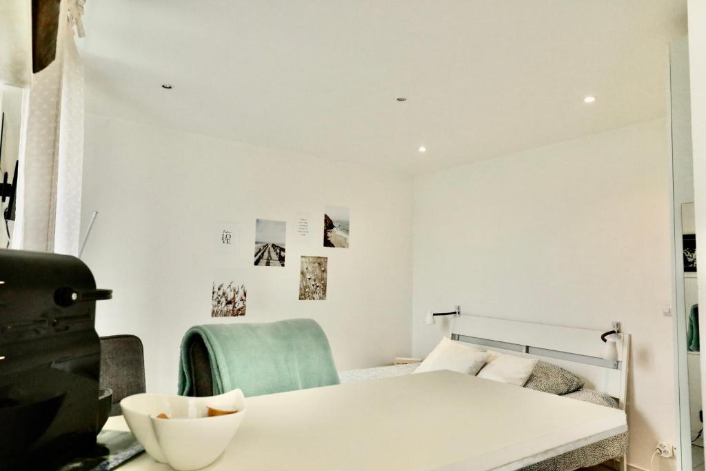 - une chambre blanche avec un lit et une chaise verte dans l'établissement Pegase, à Deauville
