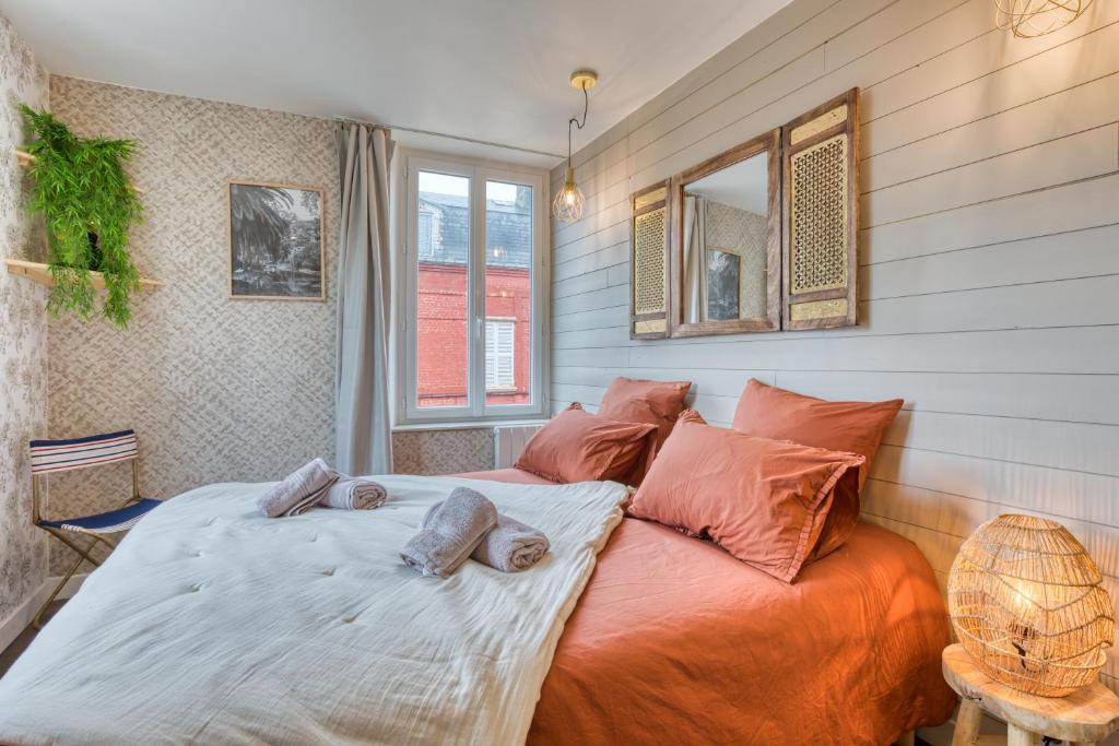 a bedroom with a bed with orange pillows at App Le Galet 5min du port in Fécamp
