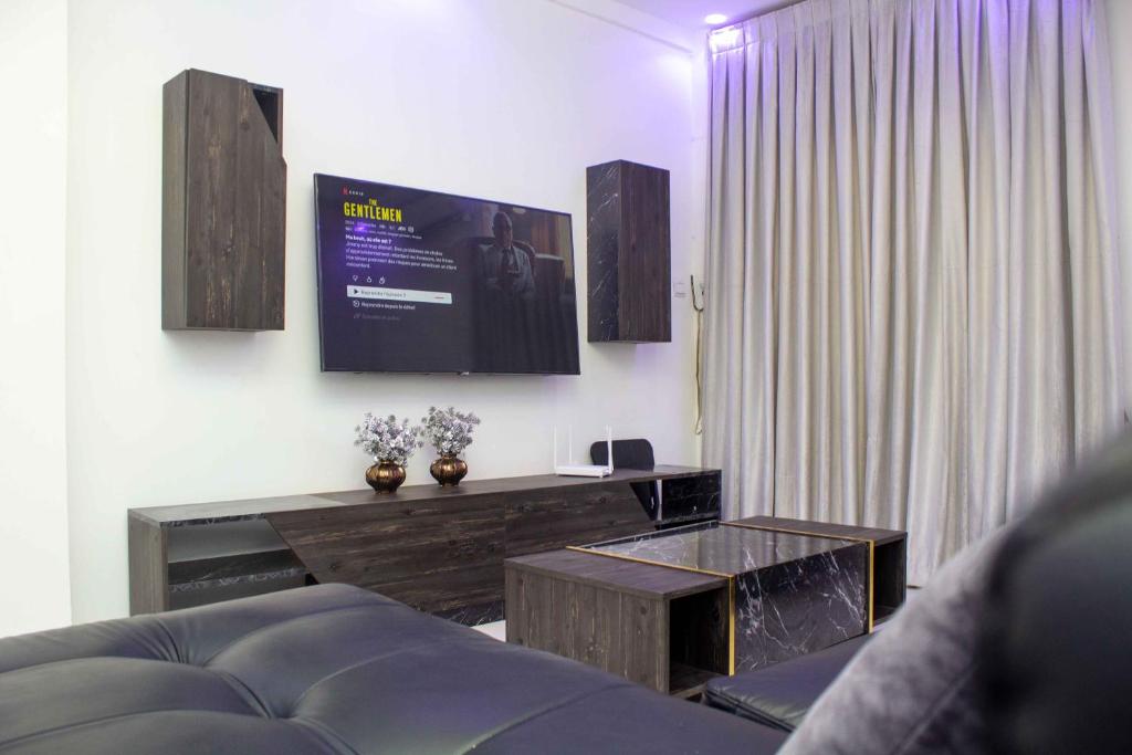 Happyhomes في داكار: غرفة معيشة مع أريكة وتلفزيون على الحائط
