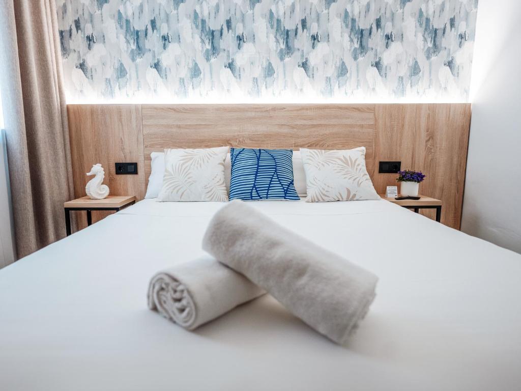 una camera da letto con un letto bianco e asciugamani di Sweet Lloret Suites a Lloret de Mar