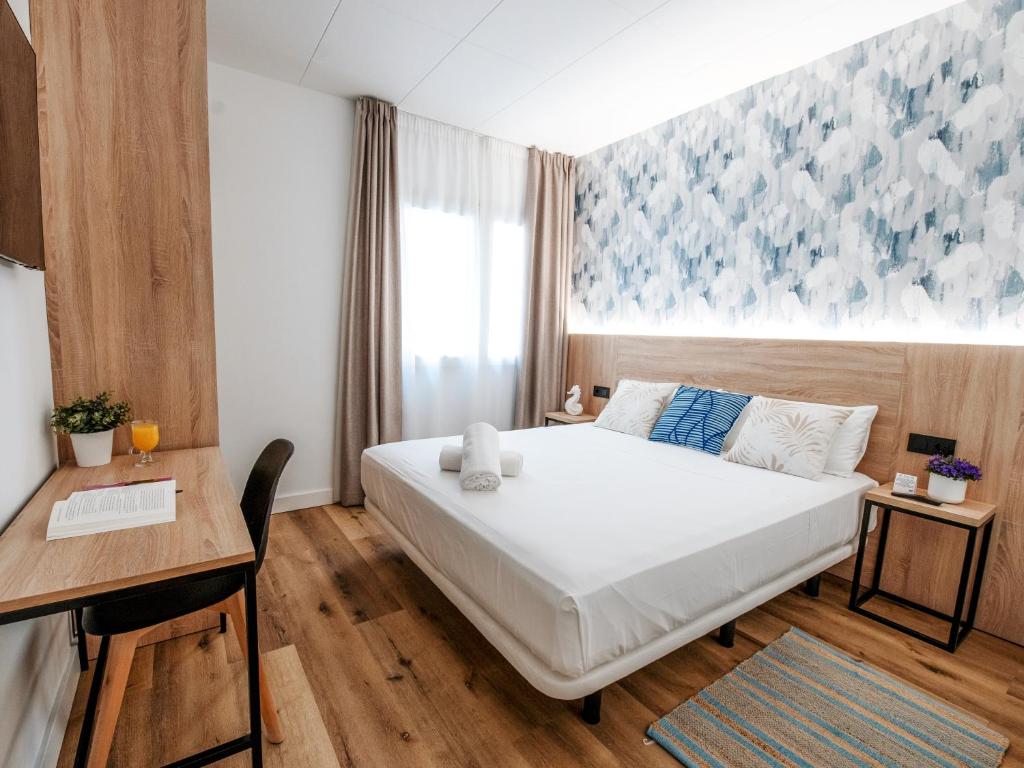 Un dormitorio con una cama y un escritorio y una ventana. en Sweet Lloret Suites, en Lloret de Mar