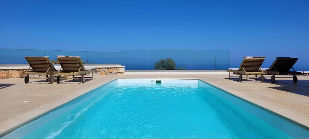 a swimming pool with lounge chairs next to at Historic Villa Kassiopi with Panoramic Sea view in Epáno Kefalás
