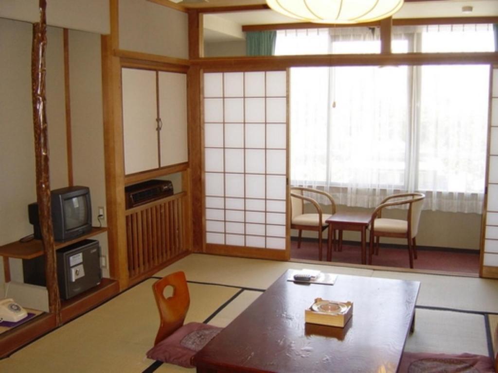 sala de estar con mesa, sillas y ventanas en Senshunraku - Vacation STAY 18450v, en Hagi