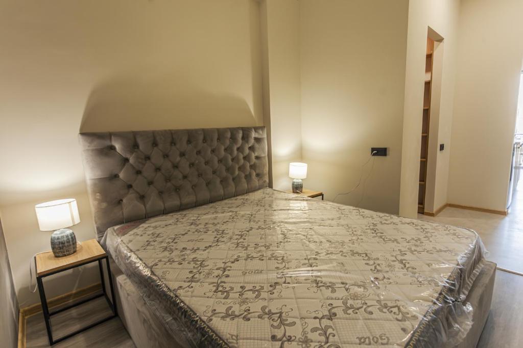 a large bed in a bedroom with two lamps at Grmagele Apartments in Tbilisi City