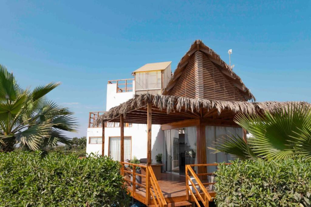 a house with a thatched roof on a beach at Luhana Chincha® Hermosa Casa de Playa in Casa Blanca