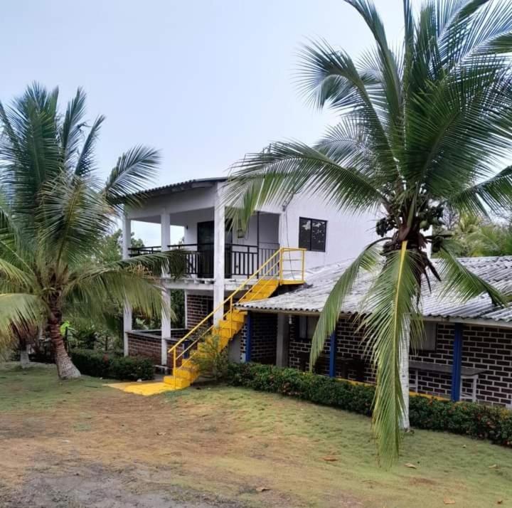 una casa con una escalera amarilla y dos palmeras en CABAÑA VILLA DEL COCO, en Arboletes
