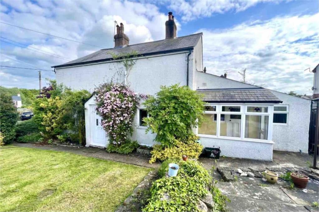 a white house with a garden in front of it at Long Lane Cottage in Broadwell