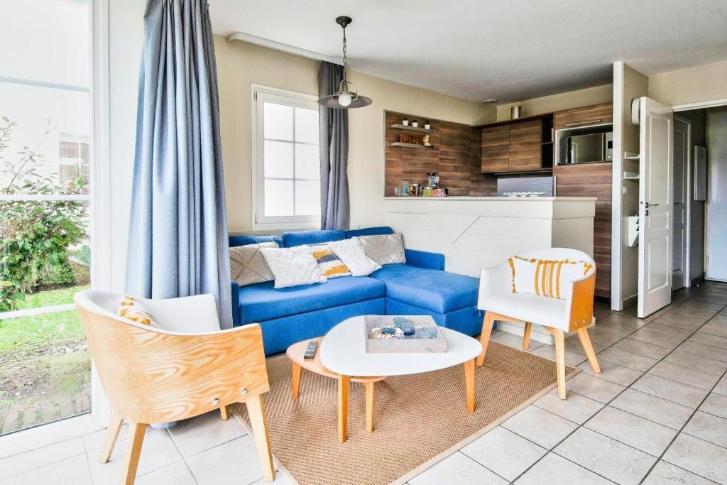 ein Wohnzimmer mit einem blauen Sofa und einem Tisch in der Unterkunft Les Maisons de Belle Dune - maeva Home - Maison 4 pièces 6 personnes Prestige MAE-2648 in Fort-Mahon-Plage