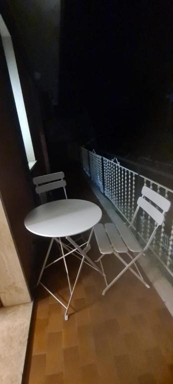 uma mesa branca e 2 cadeiras numa varanda em Casa Jiulia em Villanova dʼAlbenga