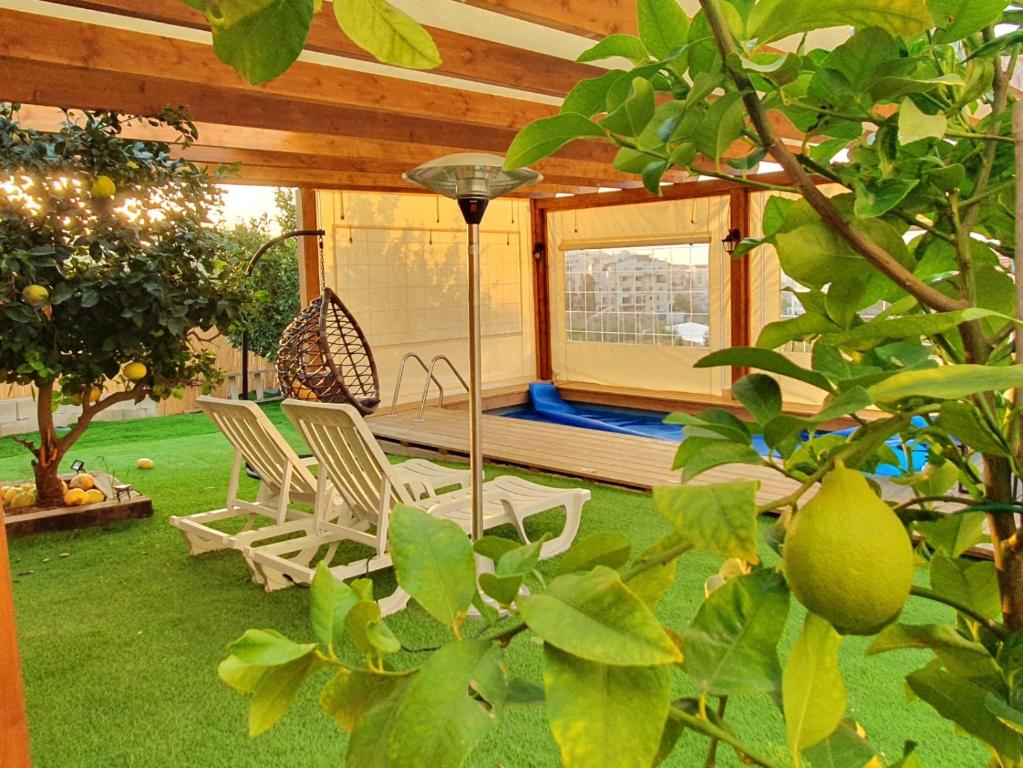 een patio met 2 stoelen en een schommel in een tuin bij וילת נופש בוטיק in Zanoaẖ
