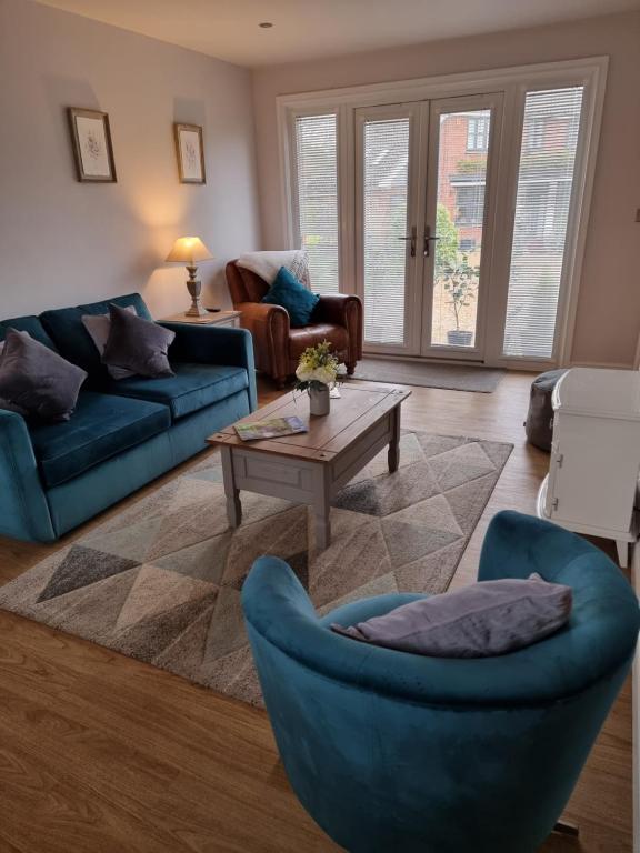 - un salon avec des canapés bleus et une table basse dans l'établissement Begonia Cottage, à Briston