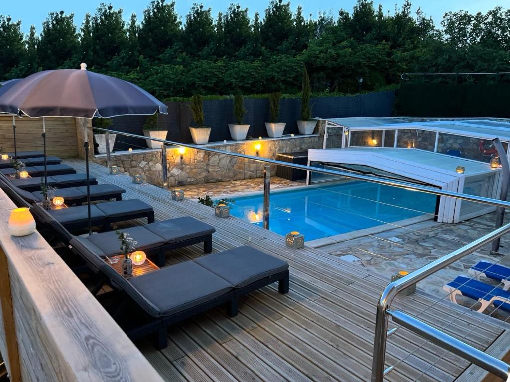 une terrasse avec une piscine, des chaises longues et un parasol dans l'établissement Hotel Don Diego, à Suances