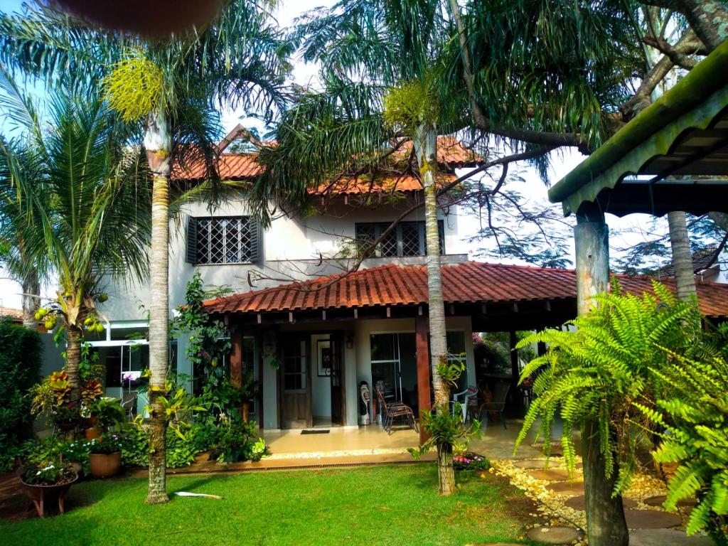 a house with palm trees in front of it at Casa Carandá in Campo Grande