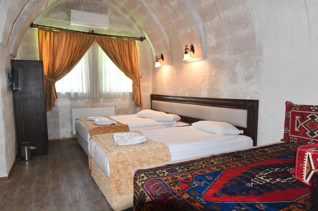 um quarto de hotel com duas camas e uma janela em Burcu Kaya Hotel em Ortahisar