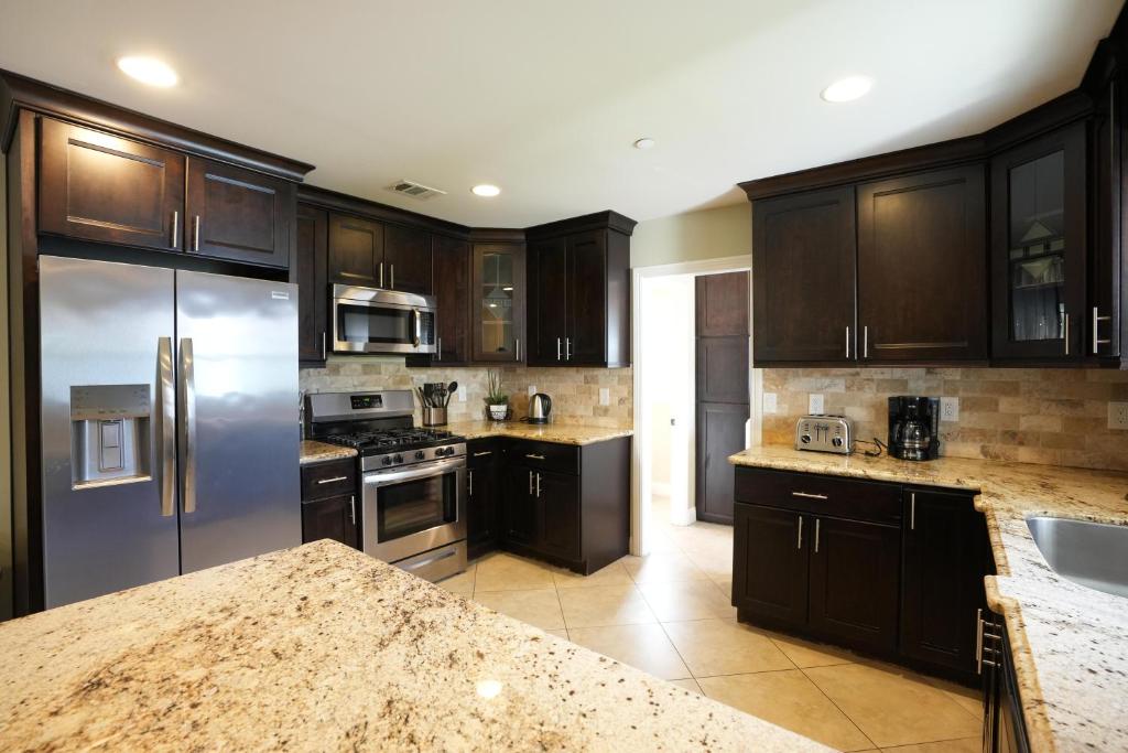 uma cozinha com armários de madeira e um frigorífico de aço inoxidável em Destination #23 em Anaheim