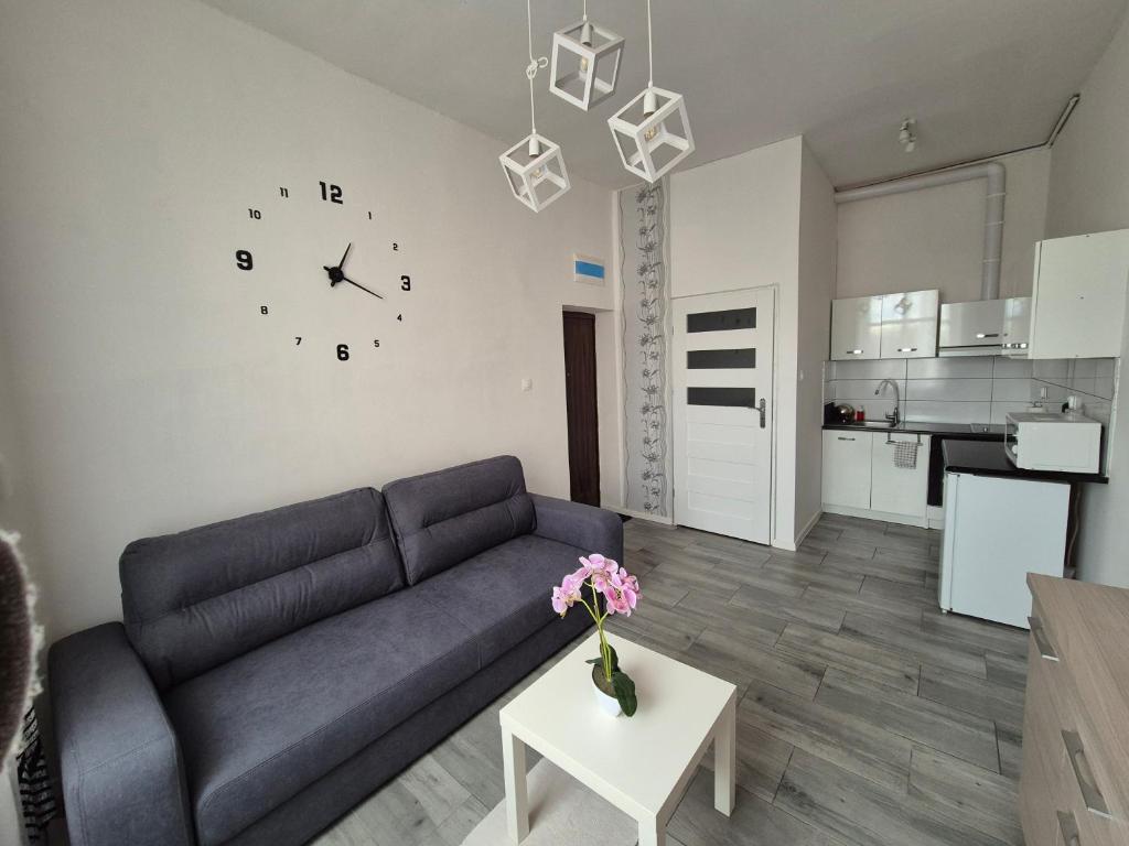 salon z kanapą i zegarem na ścianie w obiekcie Apartament w Centrum w mieście Sulechów