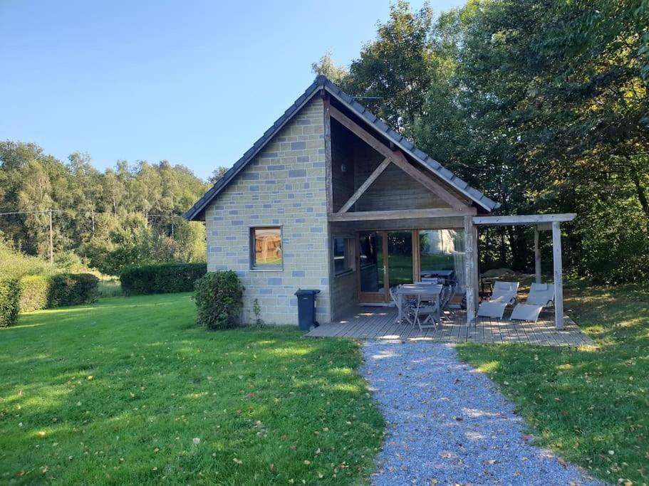 a small house with a porch and chairs in a yard at Gîte n° 20, en pleine nature, frontalier in Signy-le-Petit