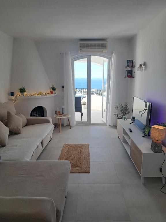 ein weißes Wohnzimmer mit einem Sofa und einem TV in der Unterkunft CASA PERSEA in Nerja