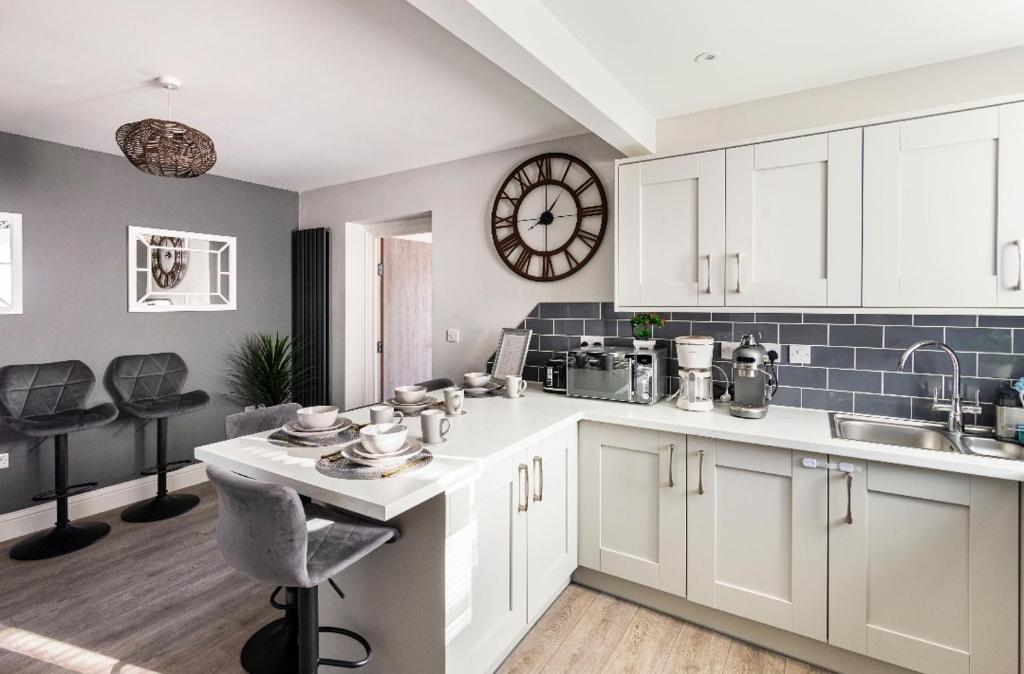 a kitchen with white cabinets and a clock on the wall at Luxury house with 4 ensuite bedrooms, free parking Wifi in Oxford