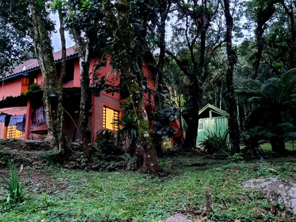 a red house in the woods with trees at Chalé do Lopo in Extrema