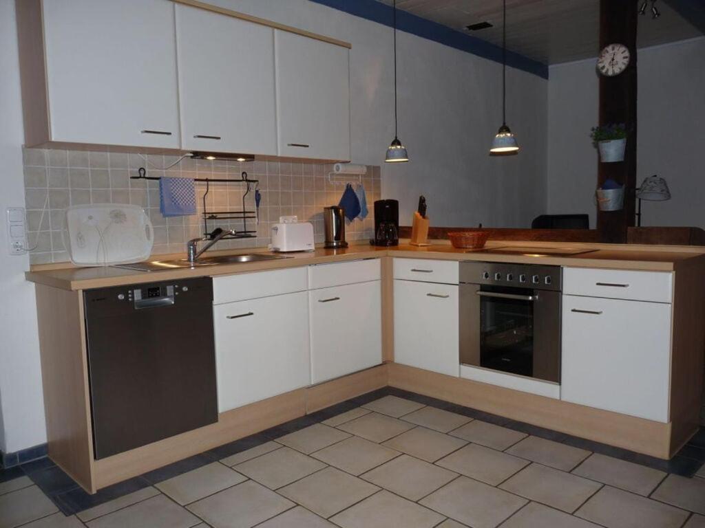 a kitchen with white cabinets and a black dishwasher at at the organic farm Angus-Hof in Stakendorf