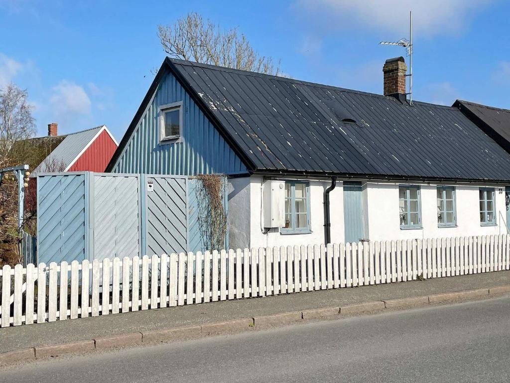 ein weißes Haus mit schwarzem Dach und einem weißen Zaun in der Unterkunft Holiday home TOMELILLA V in Tomelilla