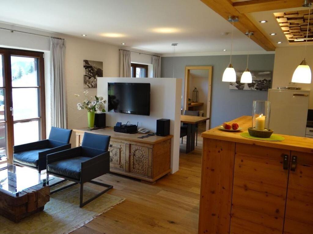 - un salon avec une télévision, un canapé et une chaise dans l'établissement Holiday apartment Sonnenkopfblick with sauna, à Fischen im Allgäu