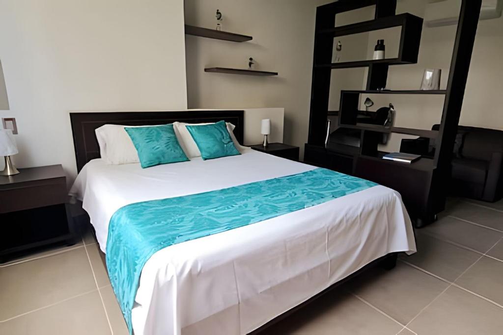 ein Schlafzimmer mit einem großen Bett mit blauen Kissen in der Unterkunft 405 Moderno Aparta-Suite en Versalles Tipo Loft - Cali Tower Suites & Lofts in Cali