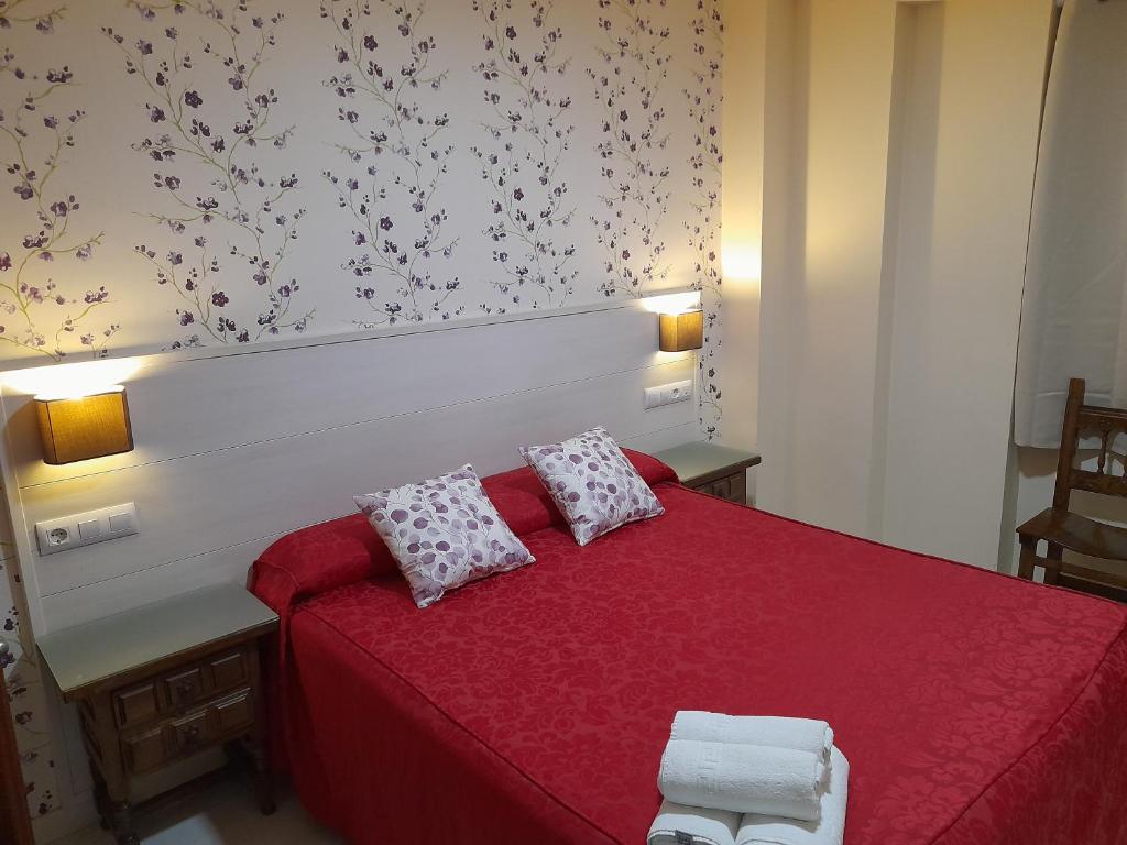 a bedroom with a red bed with two pillows at Hostal San Roque in Guadalajara