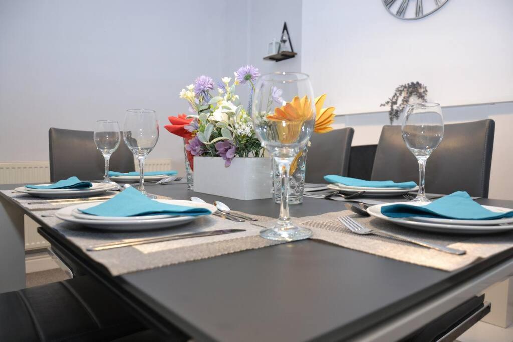 uma mesa com pratos, copos e flores em Salisbury - New 3br home, wifi, parking, sleeps 6, near Liverpool city centre em Birkenhead