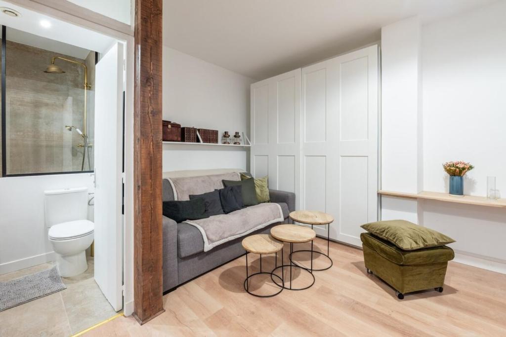 un salon avec un canapé, un lit et un tabouret dans l'établissement Beautiful Modern Studio Apartment Belleville, à Paris