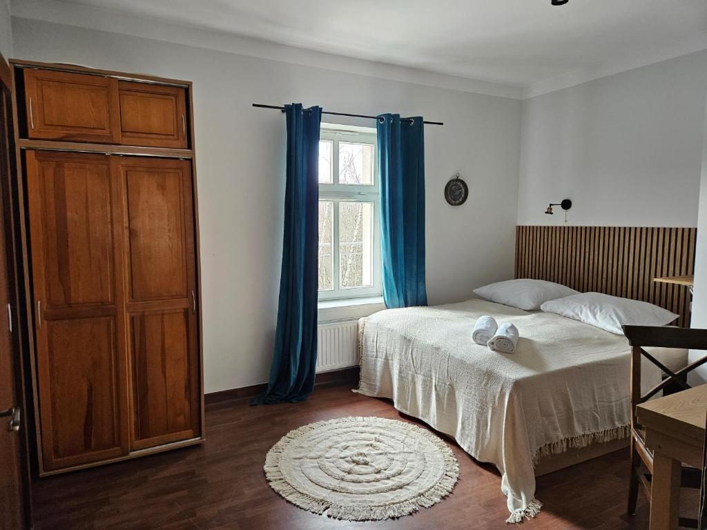 a bedroom with a bed and a window with blue curtains at Dworek Szumilas in Prudnik