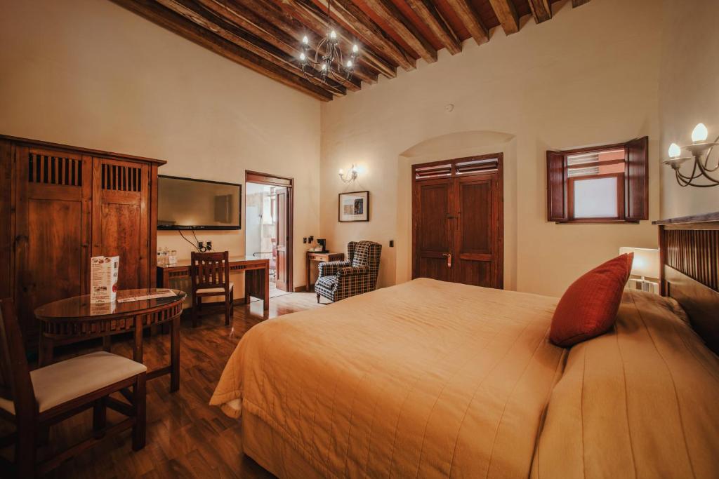 Schlafzimmer mit einem Bett, einem Schreibtisch und einem TV in der Unterkunft Hotel Casa Antigua in Oaxaca de Juárez