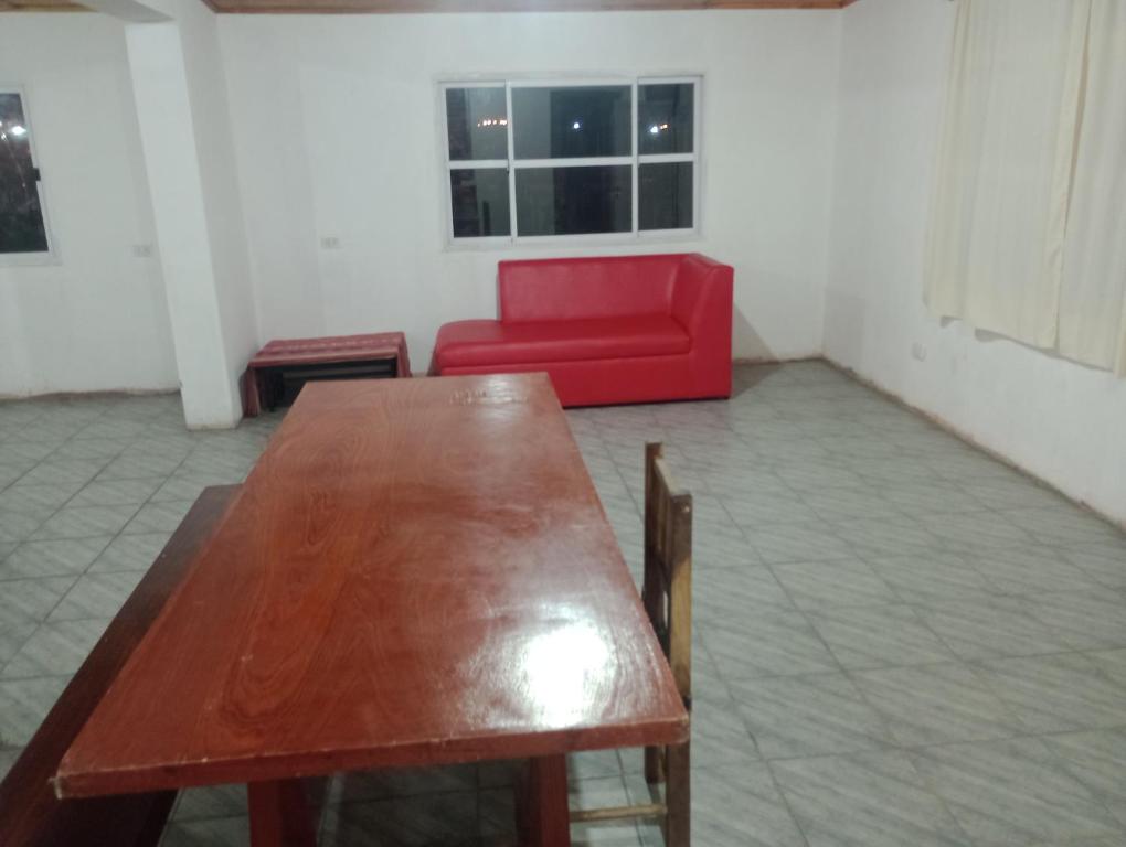 Habitación con mesa de madera y sofá rojo. en Doña Guada, en Humahuaca