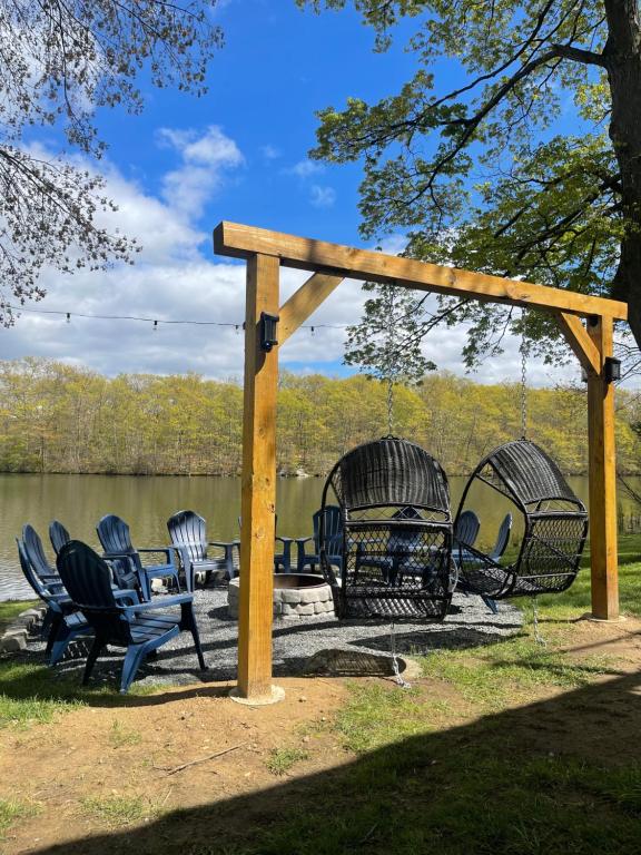 un grupo de sillas sentadas bajo una pérgola junto a un lago en Lake House Dream Views and surrounded by nature, en Vernon Township