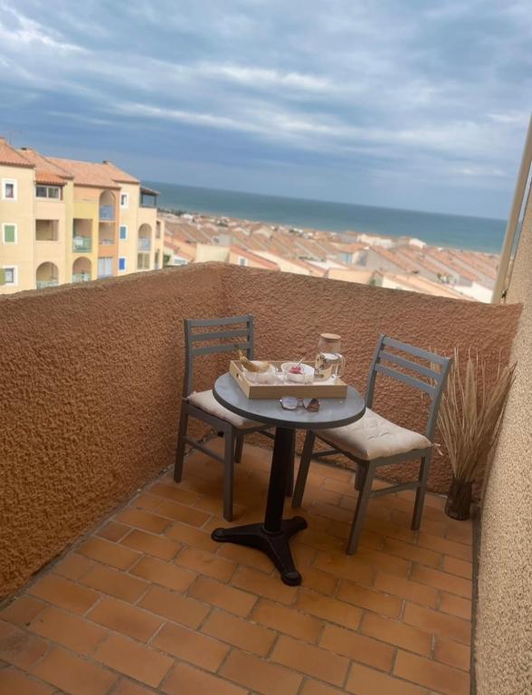 une table et des chaises sur un balcon avec l'océan dans l'établissement Appartement Saint Pierre la mer vue Mer, à Fleury