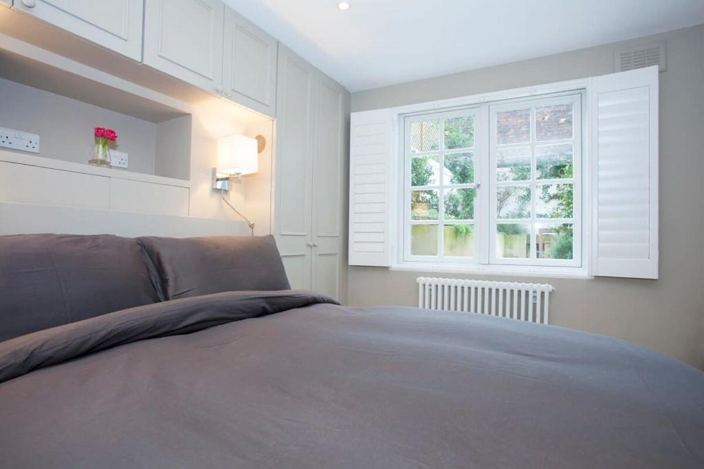 1 dormitorio con cama y ventana en Luxury 2-Bed Marylebone Georgian House with Private Garden & Office en Londres