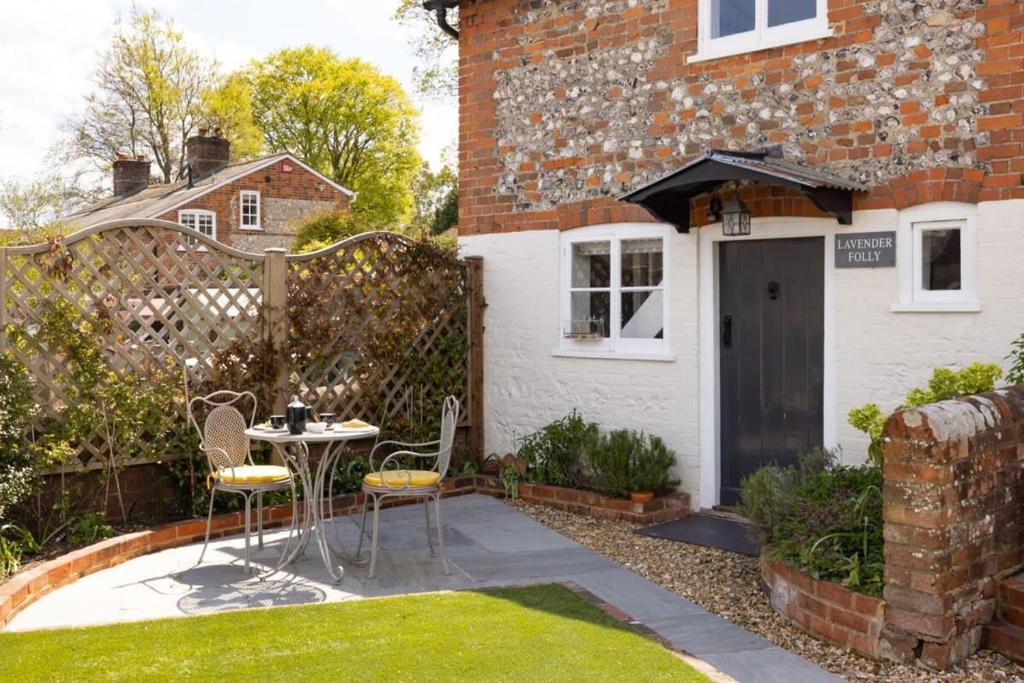a patio with a table and chairs in front of a house at The Lavender Folly - Cosy Accommodation Alresford in New Alresford