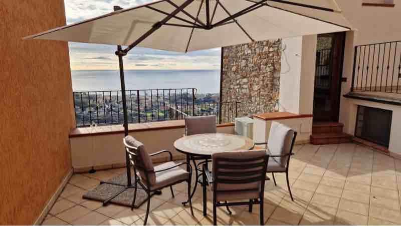 patio con tavolo, sedie e ombrellone di Maison Paradiso: Charme e relax a Pietra Ligure a Pietra Ligure