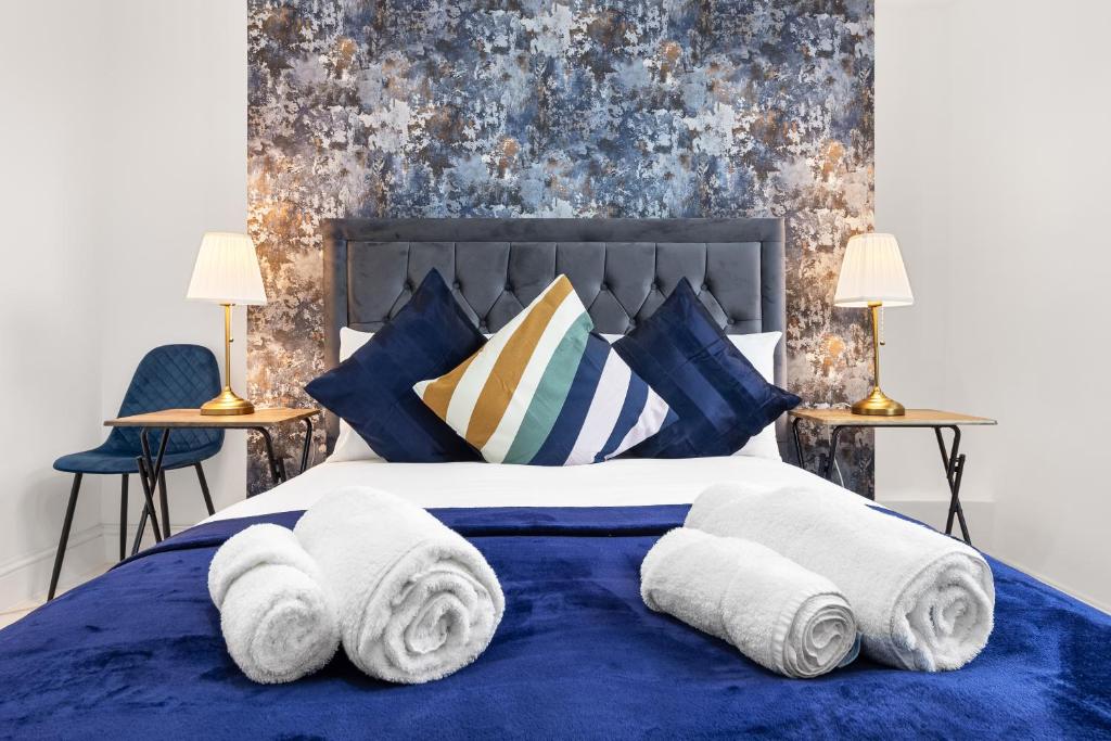 ein Schlafzimmer mit einem blauen Bett und Handtüchern darauf in der Unterkunft Modern One Bedroom Flat - Sleeps 3 - Transport Links - Finchley Road, Euston, King Cross Station - London NW3 in London