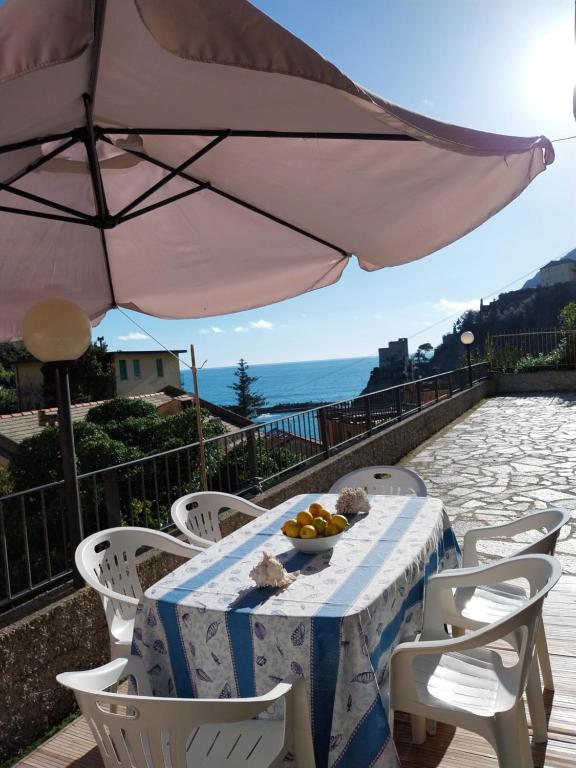 una mesa con un bol de fruta y una sombrilla en Fulvia's cozy apartment with terrace, en Monterosso al Mare