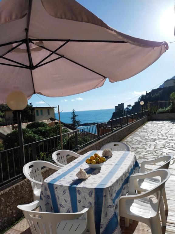 a table with a bowl of fruit and an umbrella at Fulvia's cozy apartment with terrace in Monterosso al Mare