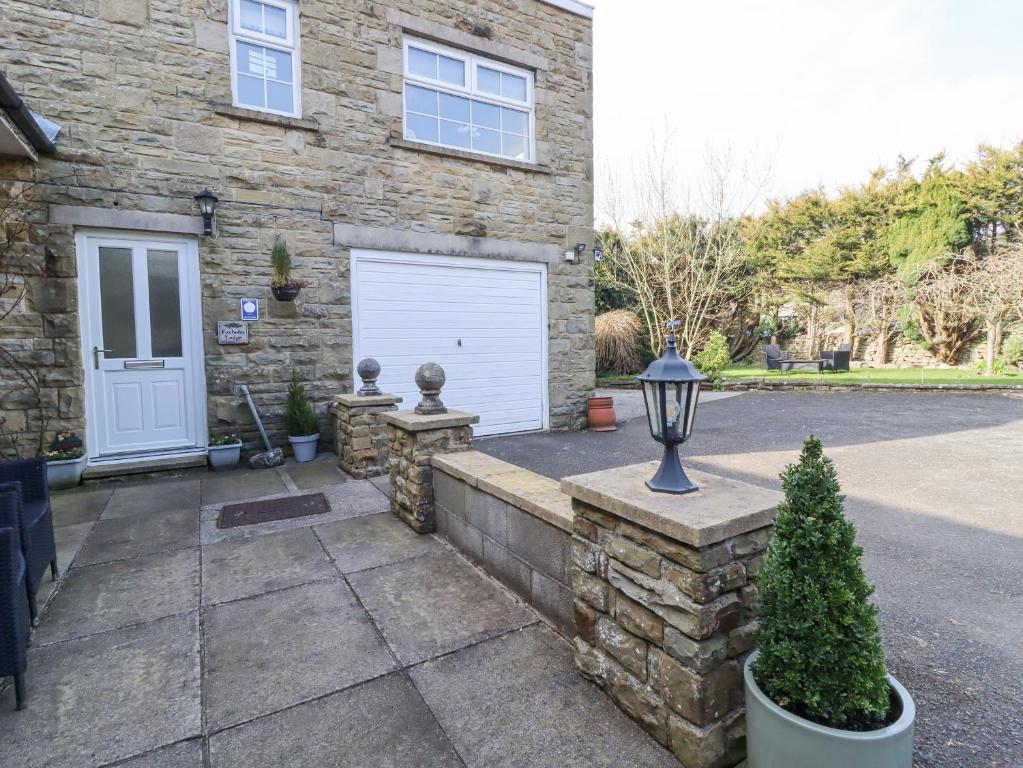 a stone house with a white garage and a driveway at Foxholes Lodge in Settle